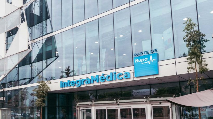 Médico especialista atendiendo a un paciente en una consulta privada dentro de un centro IntegraMédica, con equipamiento clínico moderno al fondo