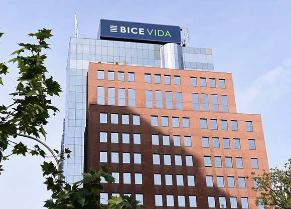 Ejecutivo de seguros atendiendo a un cliente adulto mayor en una oficina corporativa moderna, revisando documentos de cobertura