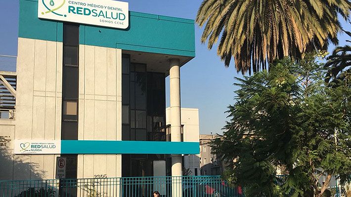 Médico especialista revisando resultados de exámenes junto a un paciente en la sala de consulta de un centro médico RedSalud